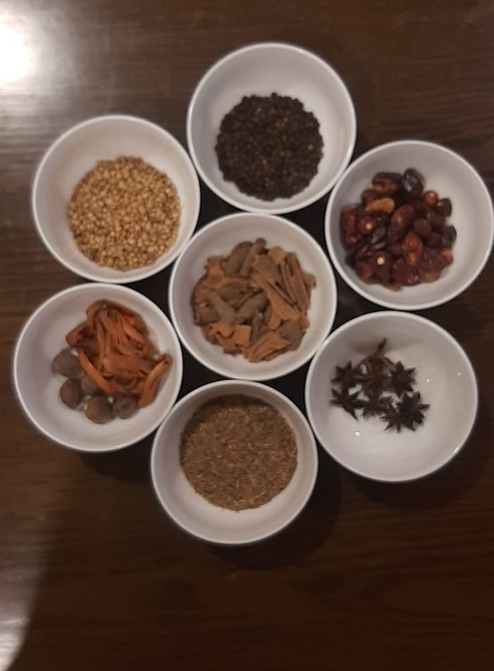 Seven whole spices in white bowls